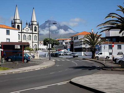 Stadtansicht von Madalena auf den Azoren, mit einer Kirche und dem Vulkan Pico im Hintergrund